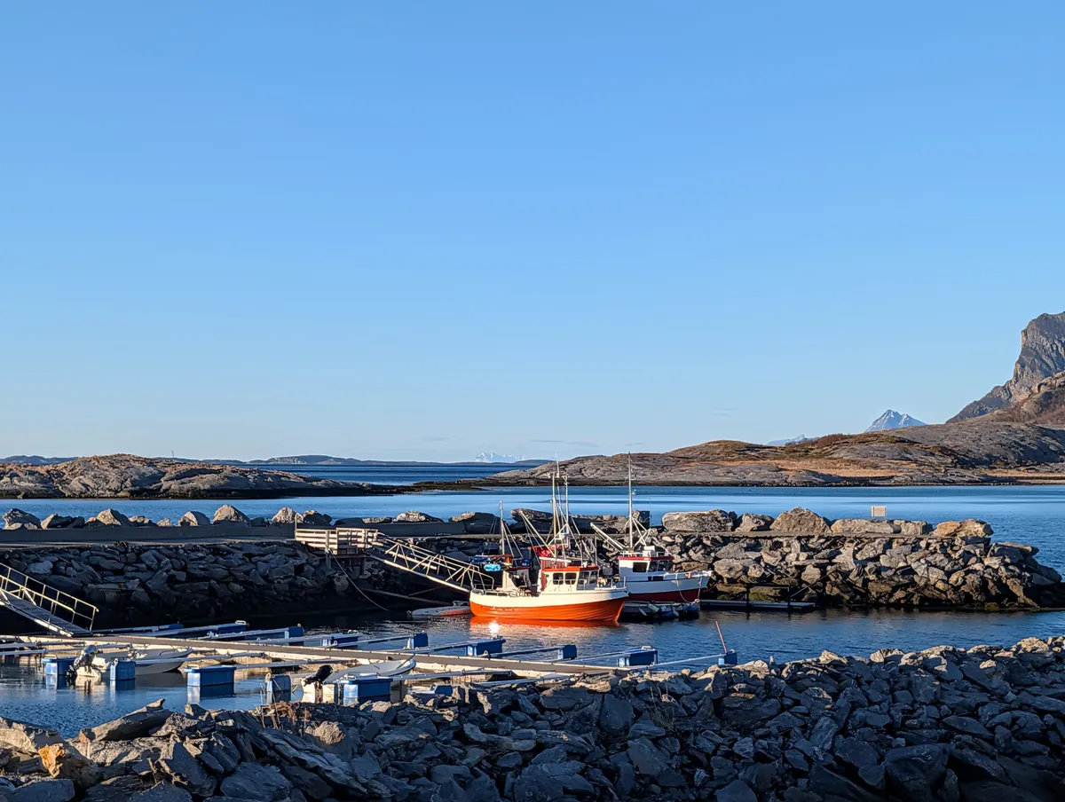 Petit port abrité avec un bateau de pêche rouge sur la côte nord de Bodø, en route vers les plages du nord et Mjellestranda.