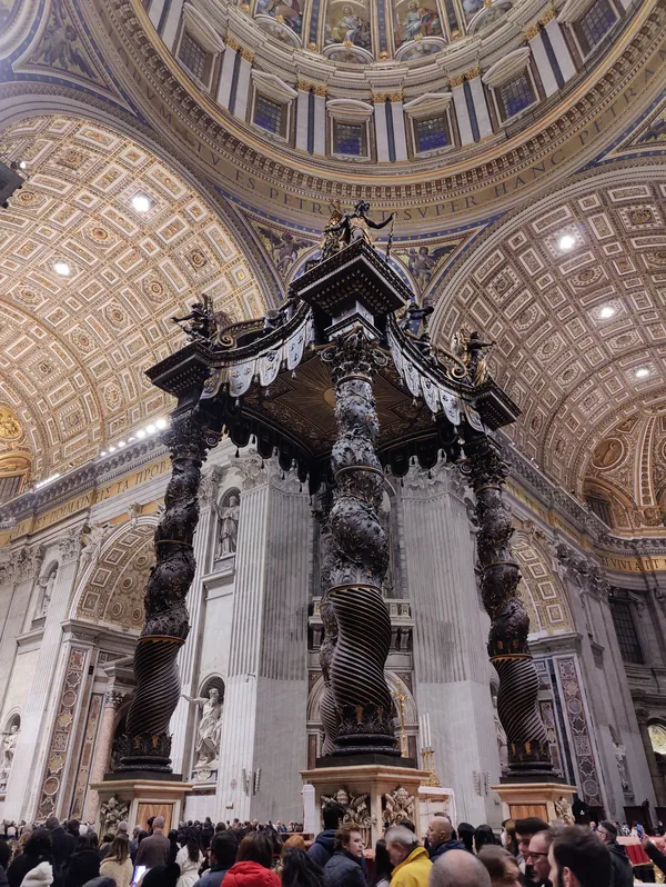 Baldaquin du Bernin entouré de visiteurs dans la nef de la Basilique Saint-Pierre au Vatican