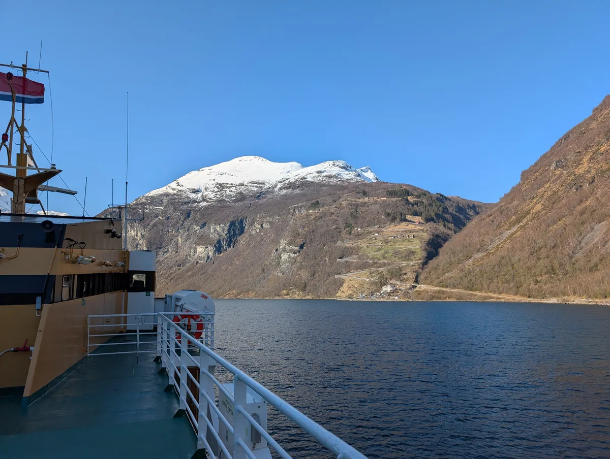 Vue depuis le pont arrière du ferry, avec le drapeau norvégien flottant au-dessus du Geirangerfjord en croisière.