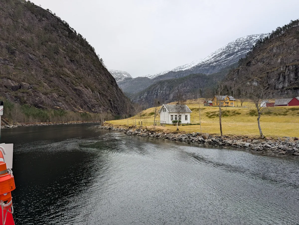 Maison blanche isolée sur le fjord en Norvège Petite maison blanche traditionnelle isolée sur une presqu'île au bord de l'Osterfjord, montagnes enneigées en arrière-plan, croisière Mostraumen.