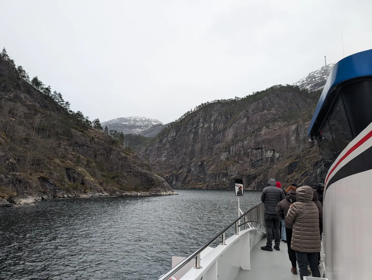 Passagers à l'approche du détroit de Mostraumen Passagers du bateau de croisière rassemblés à l'avant pour photographier le passage étroit de Mostraumen entre les falaises de l'Osterfjord.