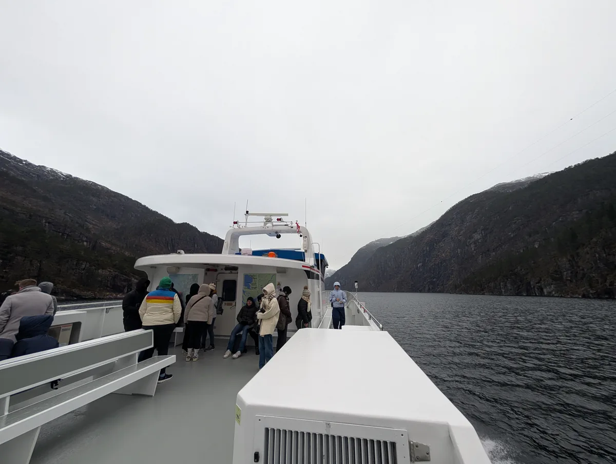 Passagers sur le pont supérieur dans Mostraumen Rodne Passagers emmitouflés sur le pont supérieur du bateau de croisière à l'intérieur du détroit étroit de Mostraumen, fjords de Bergen, Norvège.