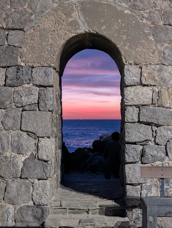 Arco de piedra antiguo en Cefalù enmarcando una puesta de sol ardiente Arco de piedra antiguo en Cefalù enmarcando una puesta de sol ardiente