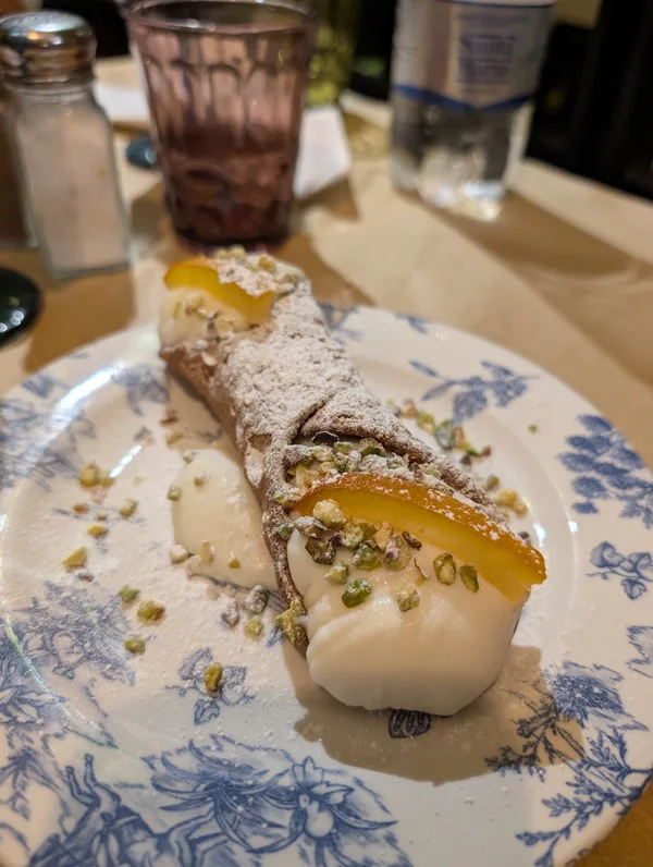 Cannolo siciliano espolvoreado con azúcar glas y guarnecido con pistachos Cannolo siciliano espolvoreado con azúcar glas y guarnecido con pistachos