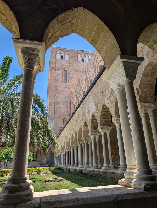 Vue du cloître de la cathédrale normande de Cefalù avec ses colonnes torsadées et sa cour ombragée en Sicile.