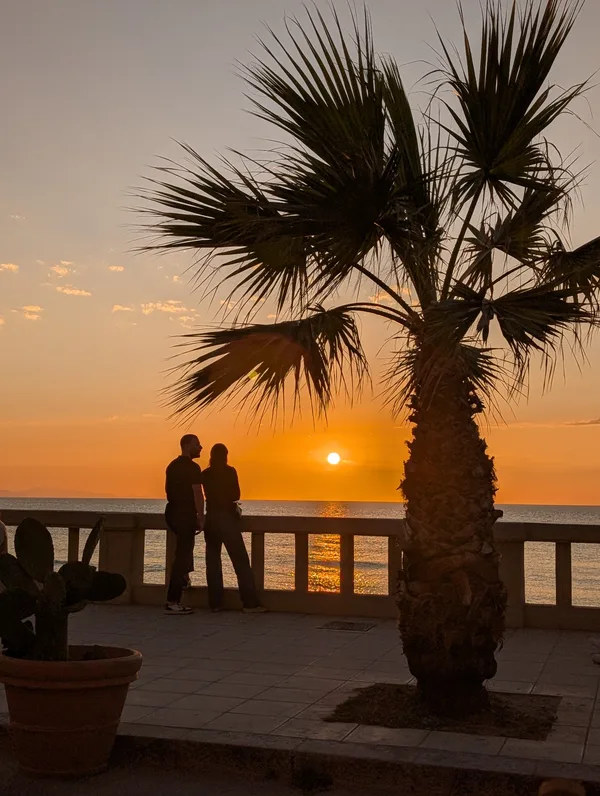 Silueta de una pareja frente a una puesta de sol ardiente en Cefalù Silueta de una pareja frente a una puesta de sol ardiente en Cefalù