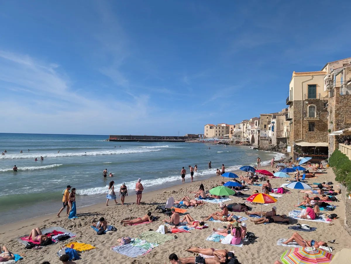 La playa de Cefalù en verano con sombrillas de colores La playa de Cefalù en verano con sombrillas de colores