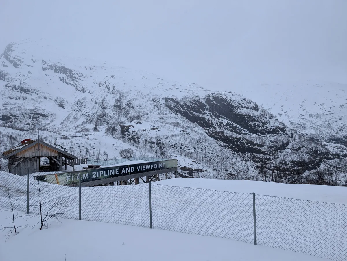 Panneau Flåm Zipline and Viewpoint au milieu des montagnes enneigées, aperçu depuis le train de Flåm près de Myrdal.