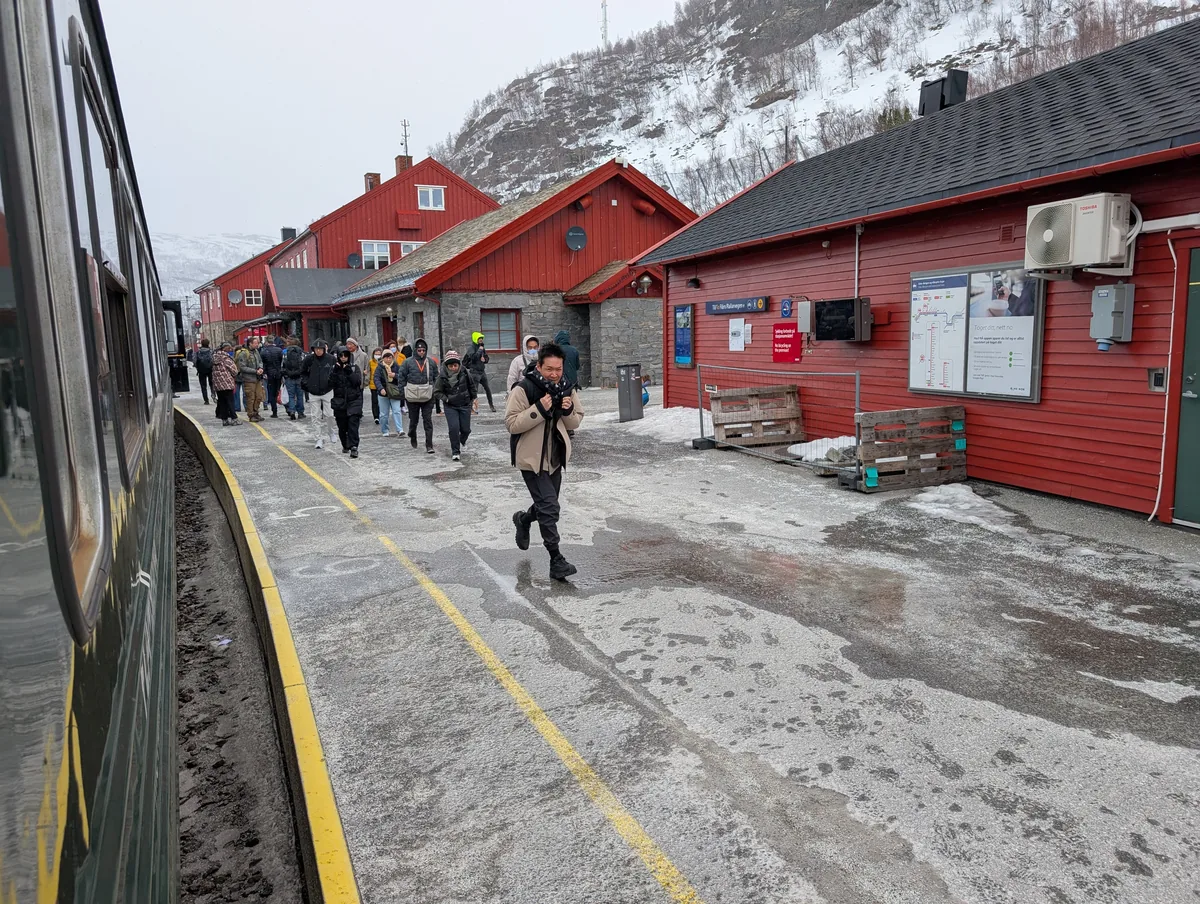 Voyageurs descendant du train sur le quai enneigé de la gare de Myrdal, devant les bâtiments rouges, terminus du train de Flåm.