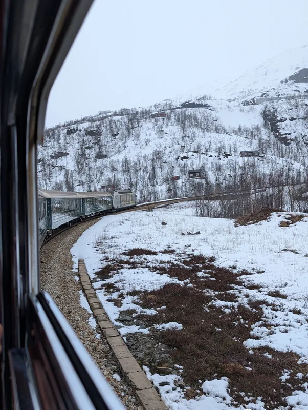 Le train de Flåm s'enroule dans un virage à travers un paysage entièrement enneigé, en approche des hauteurs de Myrdal.