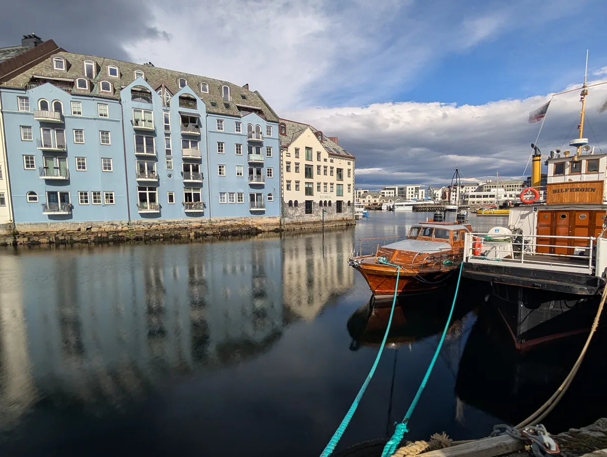 Maison bleue du canal Brosundet à Ålesund Maison Art nouveau bleue au bord du canal Brosundet avec un bateau en bois amarré au premier plan à Ålesund en Norvège.