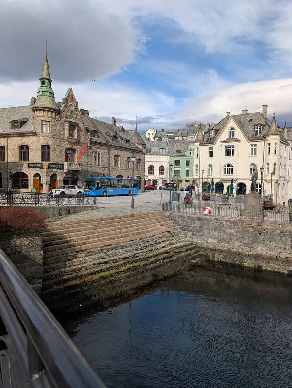 Jugendstilsenteret et place centrale d'Ålesund Le musée Jugendstilsenteret dominant une place pavée d'Ålesund avec un bus bleu Fram et une statue, en Norvège.