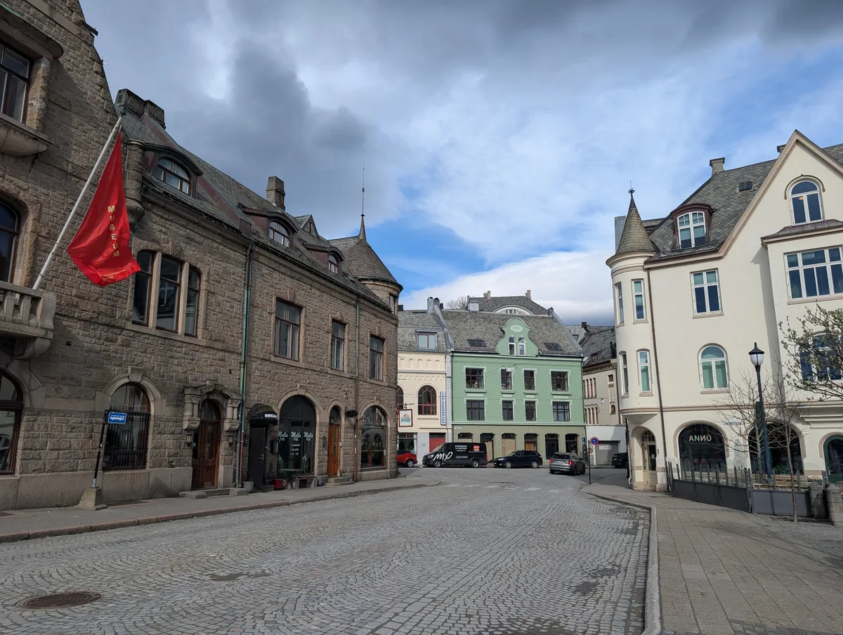 Place pavée du centre d'Ålesund Place pavée du centre historique d'Ålesund entourée de bâtiments Art nouveau et bordée du canal, en Norvège.