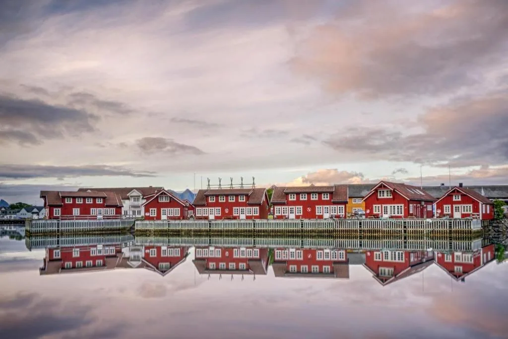 Rorbu rojos del Anker Brygge en una pequeña isla en medio del puerto de Svolvær, con auroras boreales en las Lofoten (Noruega)