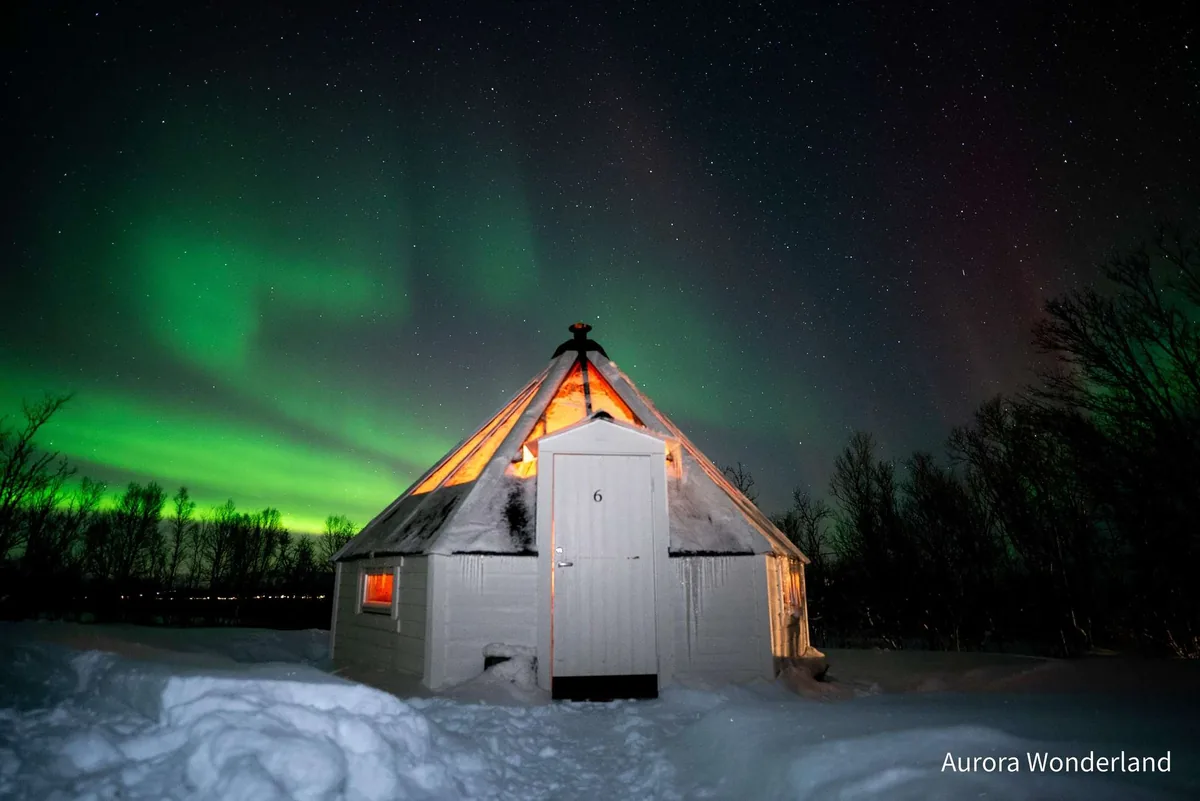 Moto de nieve y noche en lavvo de cristal Aurora Wonderland en los Alpes de Lyngen en Tromsø