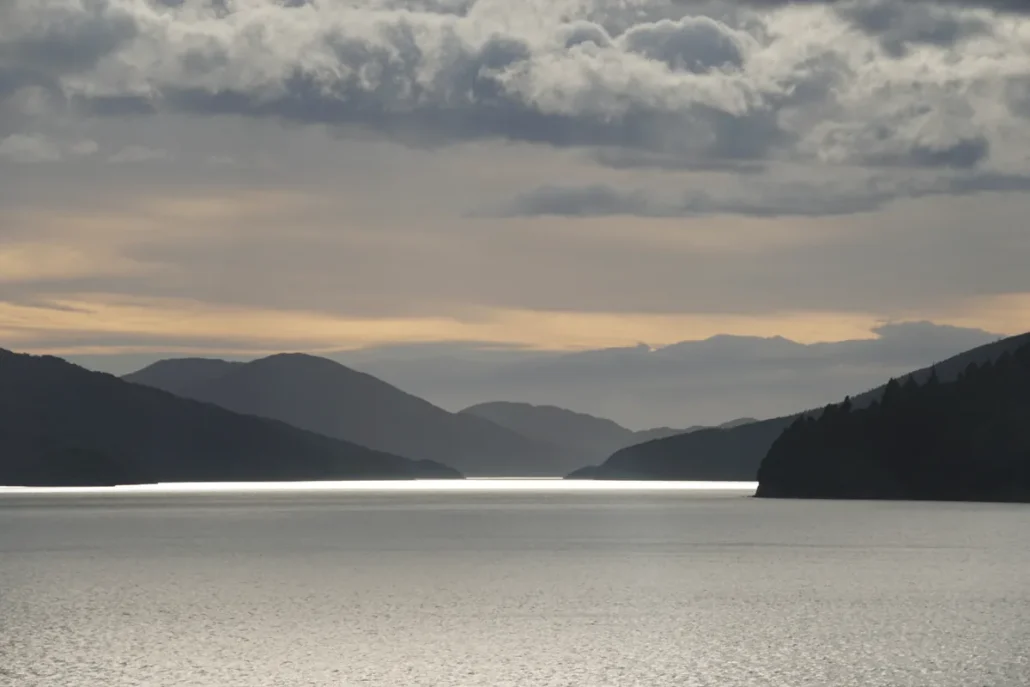 Band of light on the water and backlit hills in the Marlborough Sounds, during the ferry crossing towards Picton.