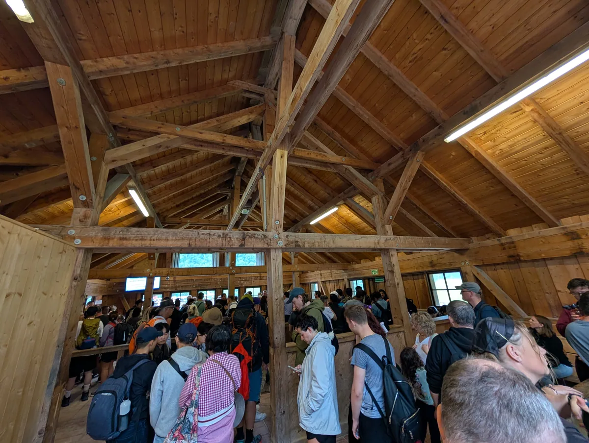 File d'attente à l'embarquement du Königssee Voyageurs patientant sous la charpente en bois de l'abri d'embarquement avant de monter dans le bateau du Königssee.
