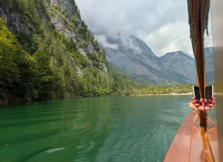 Visiter le Königssee : le guide complet (tarifs et horaires 2026) Eau vert émeraude du Königssee au pied d'une paroi boisée, vue depuis le pont du bateau électrique.