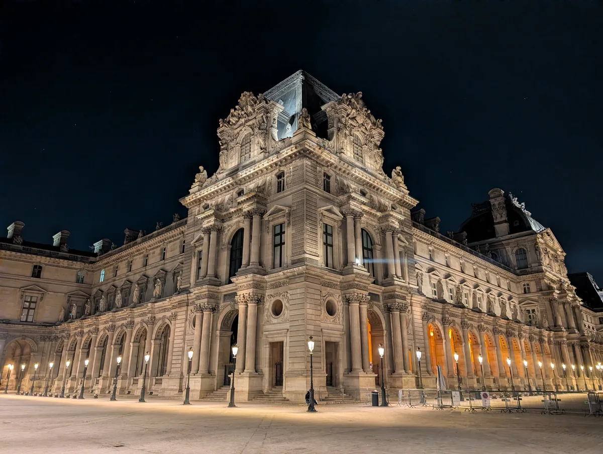Façade of the Louvre palace lit up at night Sculpted façade of a pavilion of the Louvre palace lit up at night, lampposts lined along the deserted courtyard in Paris.