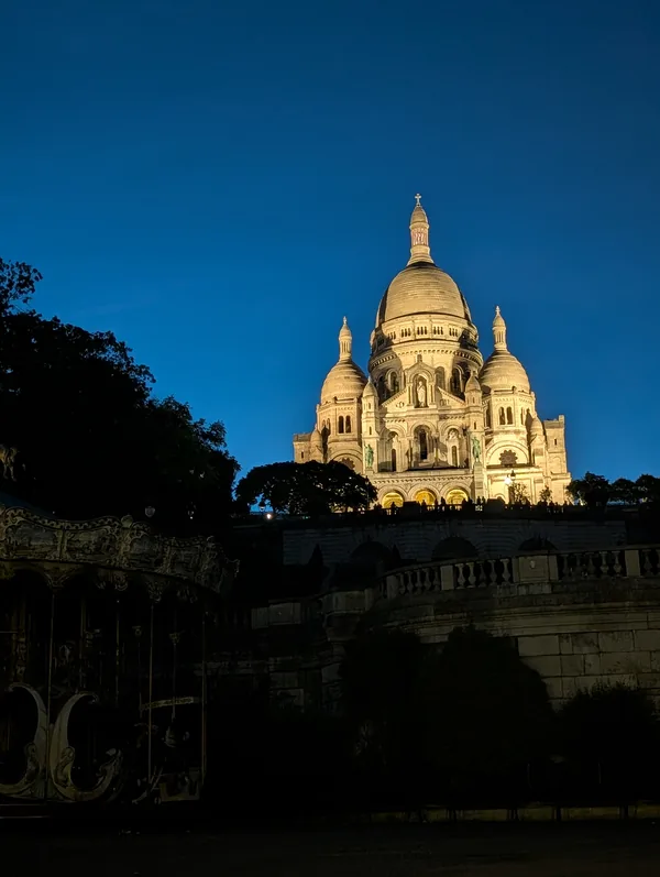 The Sacré-Cœur and the Montmartre carousel at night The Sacré-Cœur basilica lit up atop the Montmartre hill at night, with the carousel in the foreground in Paris.