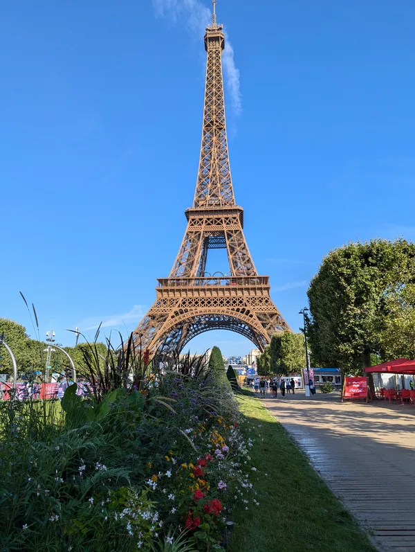The Eiffel Tower from the flower-filled Champ-de-Mars The Eiffel Tower seen from the paths of the Champ-de-Mars, with a bed of colourful flowers in the foreground on a sunny morning.