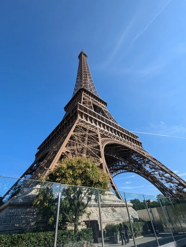 The Eiffel Tower from below against a blue sky The Eiffel Tower photographed from below at its base, its metal structure standing out against a cloudless blue sky in Paris.