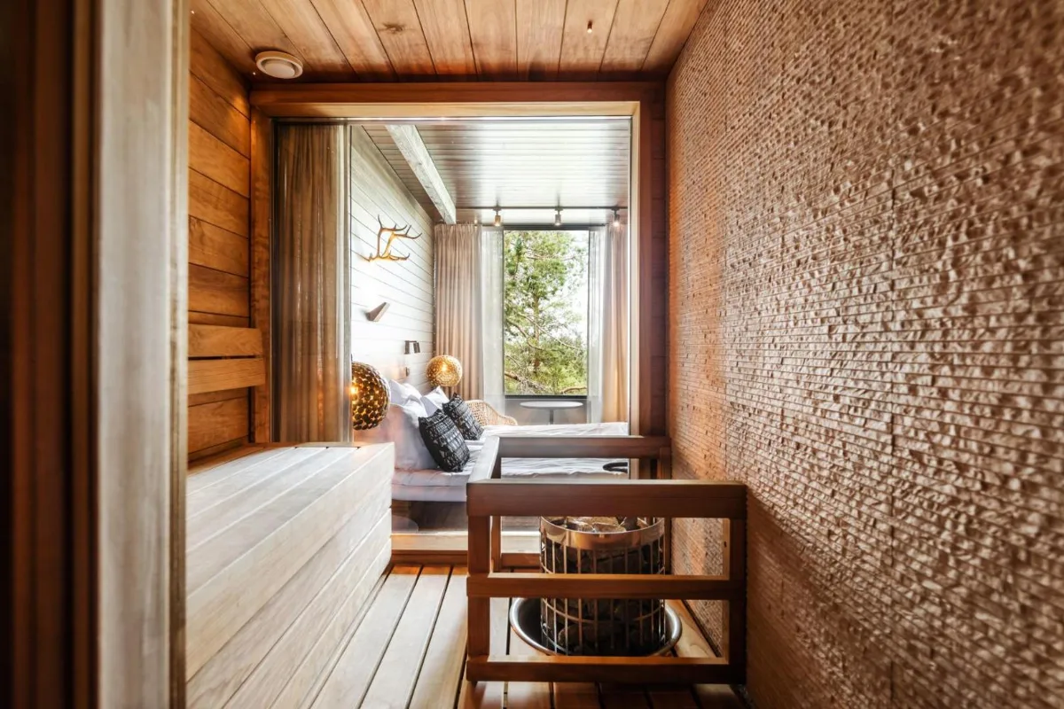 Chambre avec sauna privé du Lapland Hotels Sky Ounasvaara à Rovaniemi, lit face à une baie vitrée ouverte sur la forêt de pins