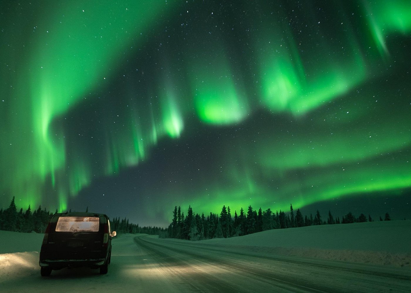 Nordlicht-Fotojagd mit Nordic Odyssey in Rovaniemi: Kleingruppe mit max. 8 Personen am Lagerfeuer mit gegrillten Würstchen und heißer Schokolade, der Guide macht die Fotos mit der Spiegelreflexkamera