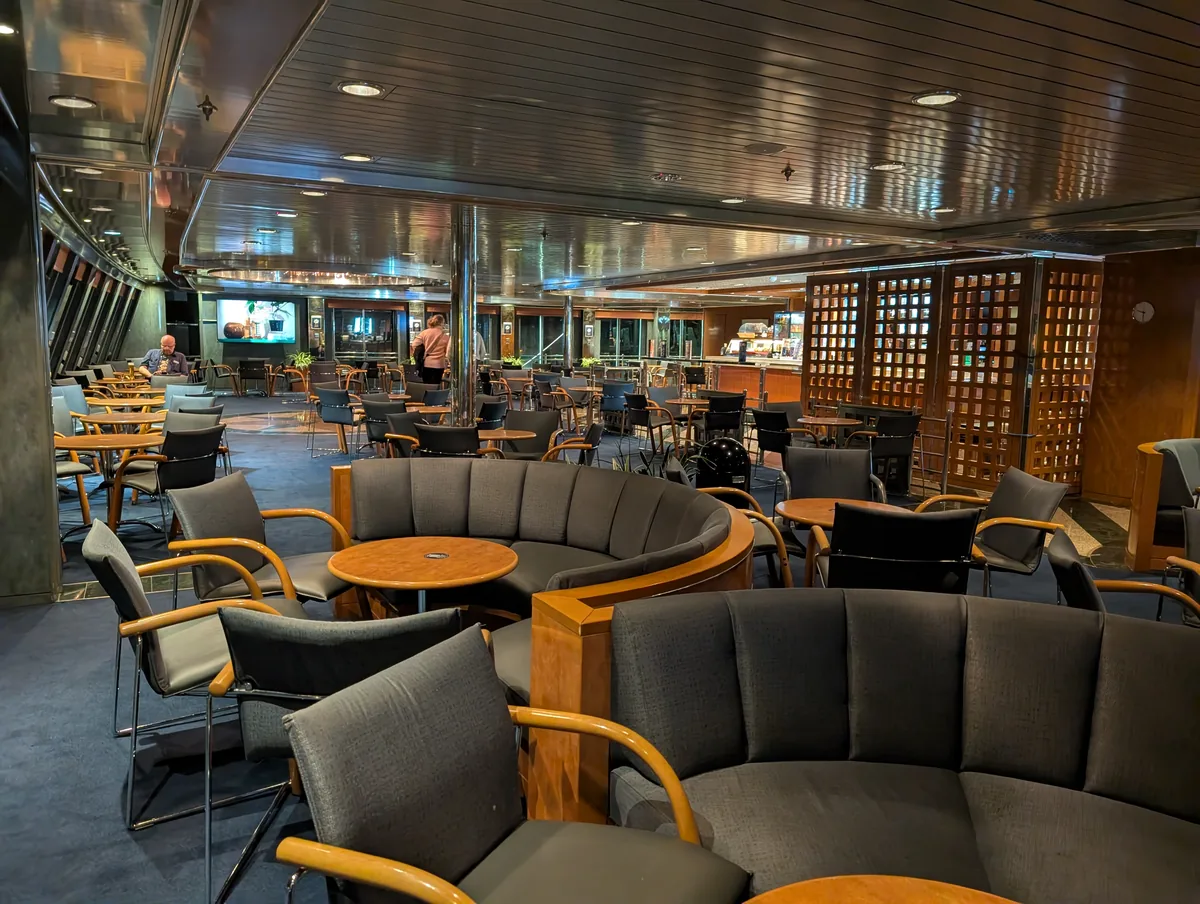 Bar-Lounge der Fähre Tinker Bell mit runden Sitzbänken, Holztischen und Bildschirmen während der Überfahrt Travemünde–Trelleborg