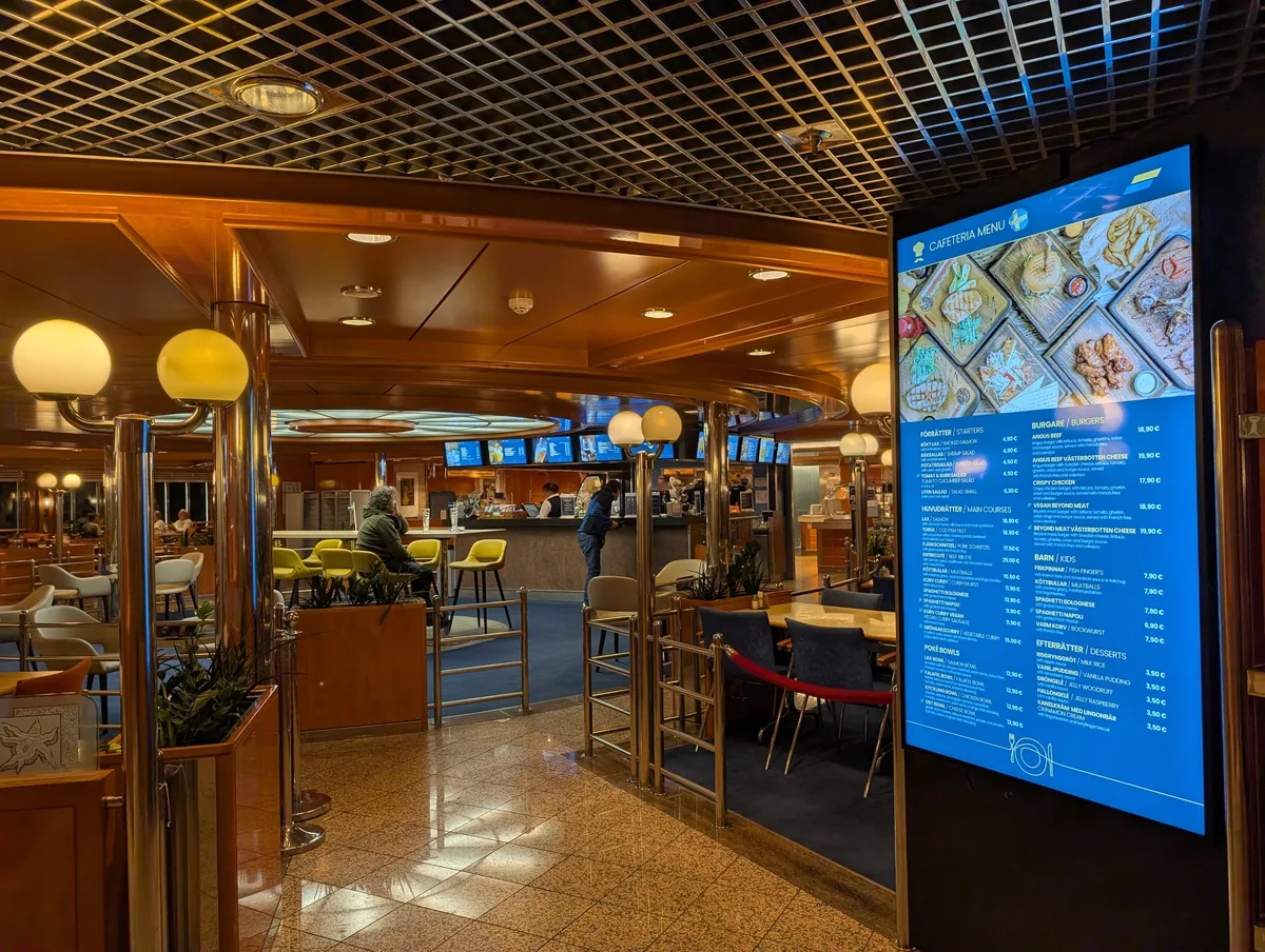 Bildschirm mit der Speisekarte der Cafeteria an Bord der TT-Line-Fähre Tinker Bell, mit Gerichten und Preisen während der Überfahrt