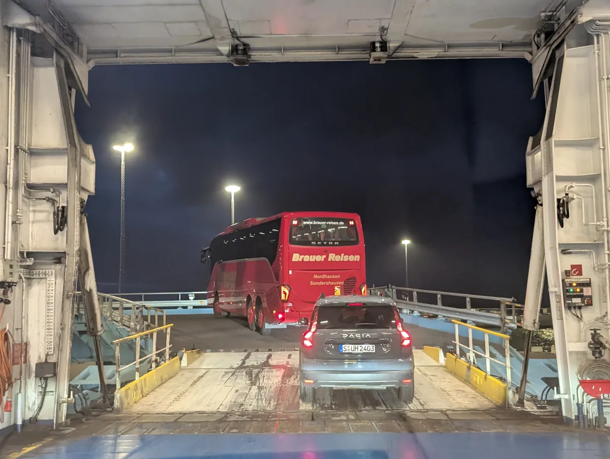 Autos und Reisebus verlassen die TT-Line-Fähre frühmorgens über die Heckrampe, bei der Ankunft im Hafen Trelleborg in Schweden