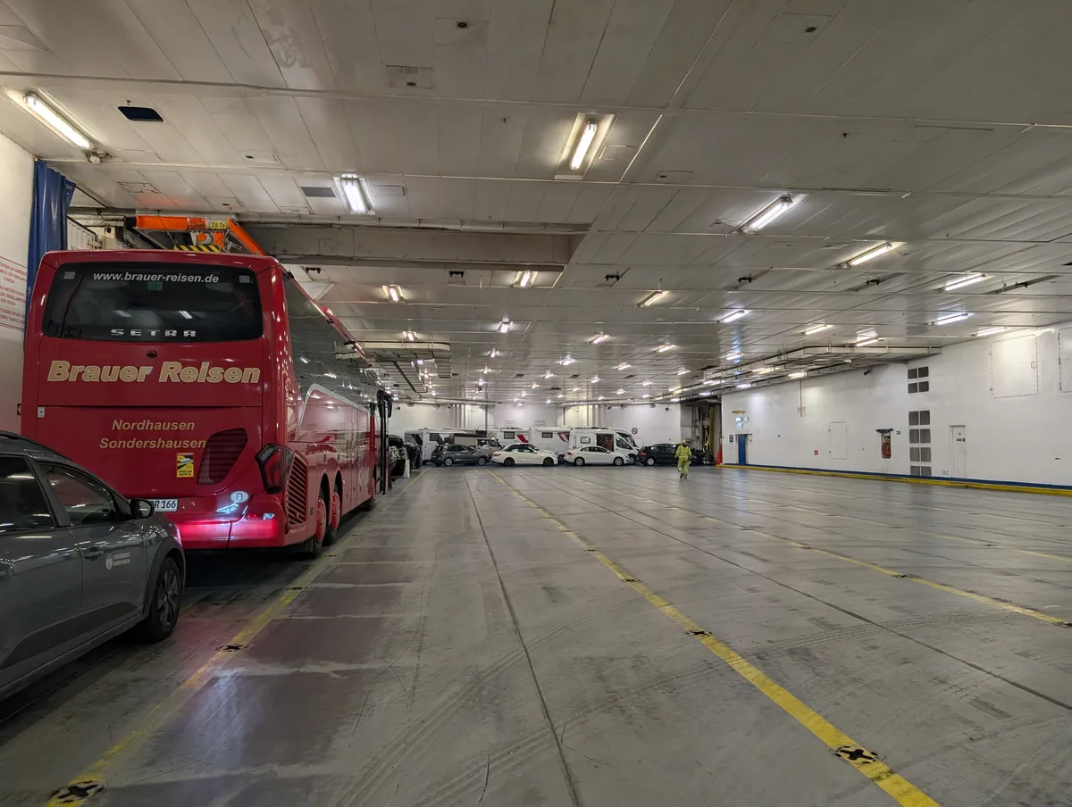 Roter Reisebus und Autos im großen Autodeck der TT-Line-Fähre Tinker Bell während der Überfahrt Travemünde–Trelleborg