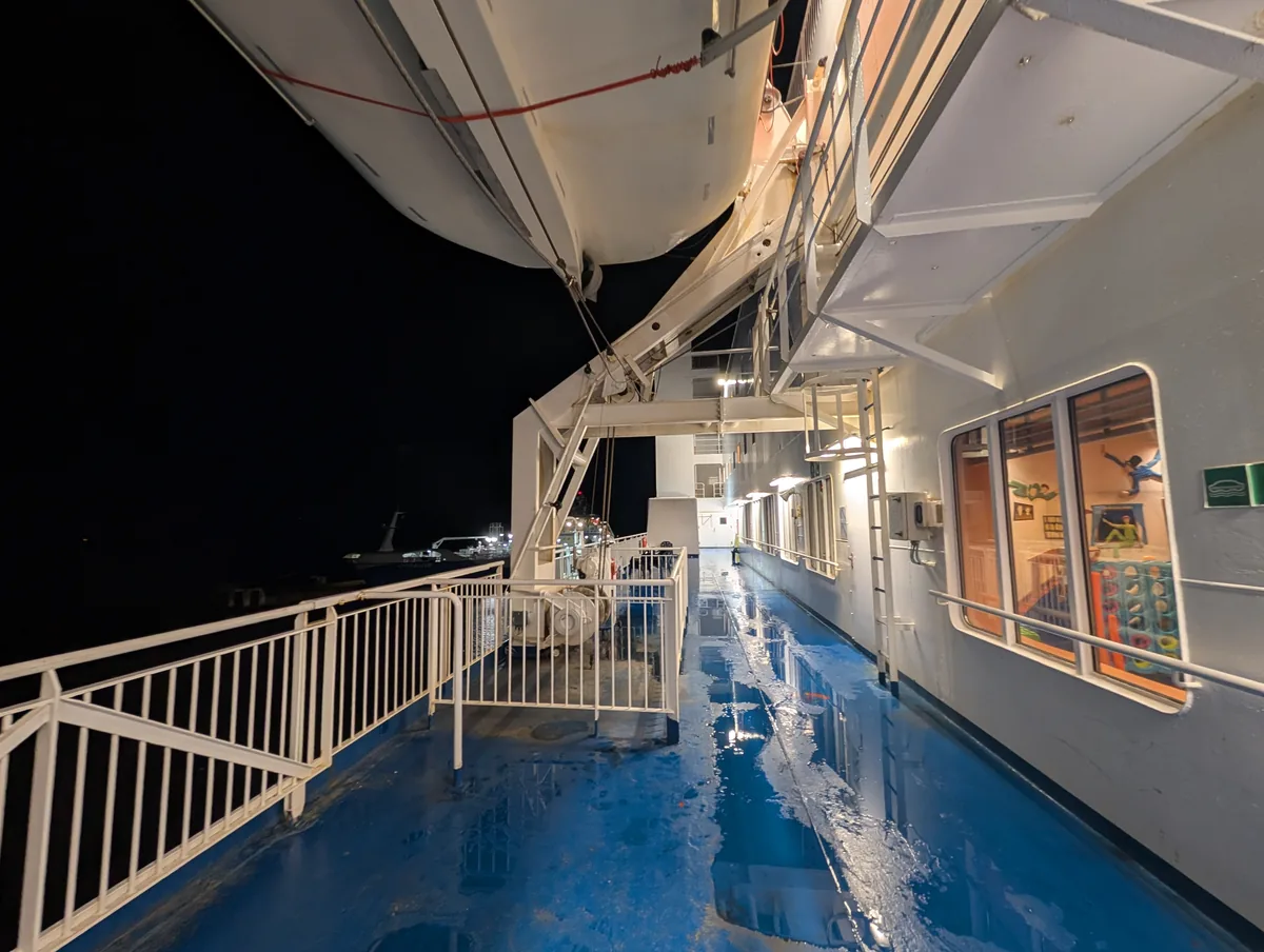 Regennasses Promenadendeck unter den Rettungsbooten der Fähre Tinker Bell, nachts im Hafen Travemünde vor der Abfahrt