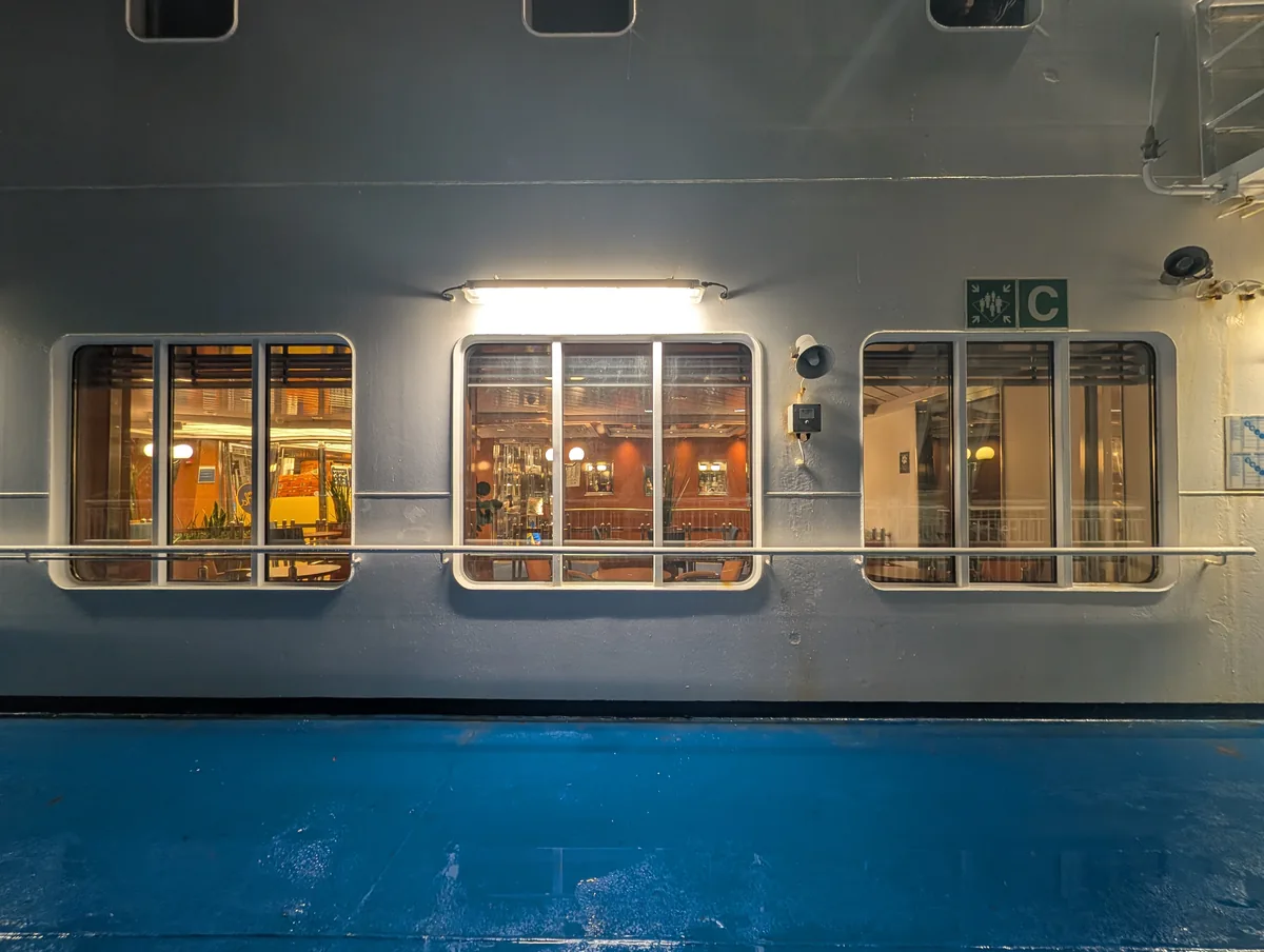 Blaues Außendeck der Fähre Tinker Bell bei Nacht, mit den beleuchteten Fenstern der Lounge auf dem Weg von Travemünde nach Trelleborg