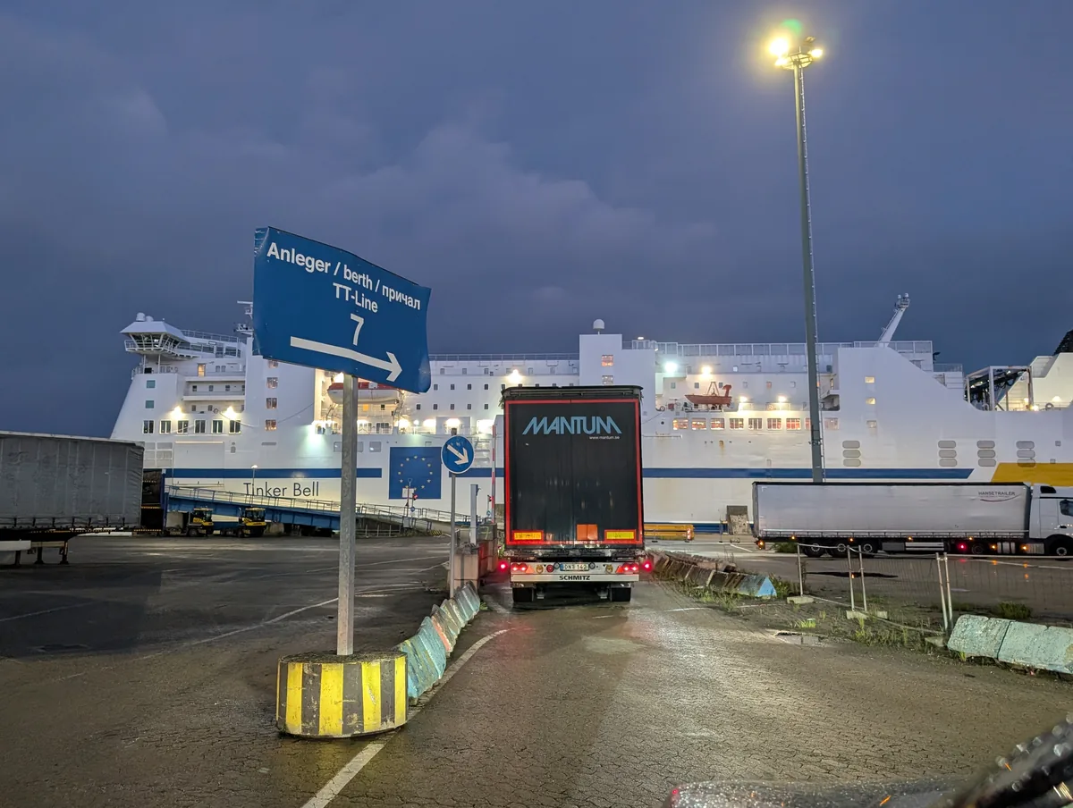 Schild von Anleger 7 vor der Fähre Tinker Bell im Hafen Travemünde, davor ein Lkw, der auf das Einschiffen wartet
